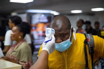 Coronavirus. Un calator este consultat si i se ia temperatura pe un aeroport din Lagos